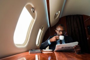 American businessman reading business newspaper while drinking coffee in private plane