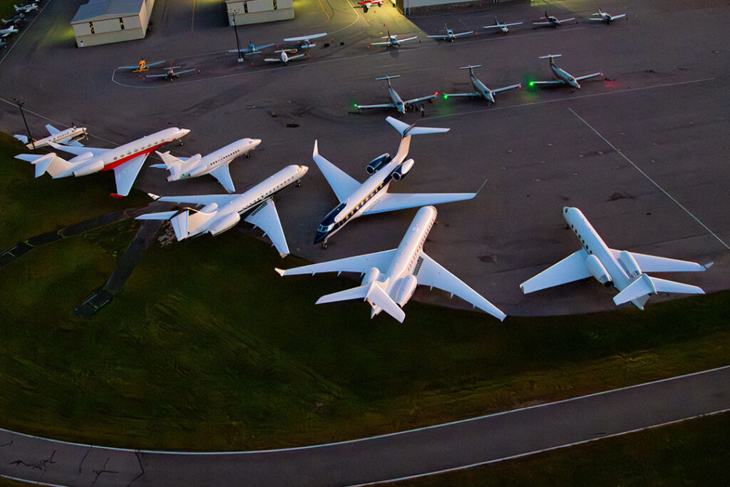 A group of private jets parked on the tarmac 