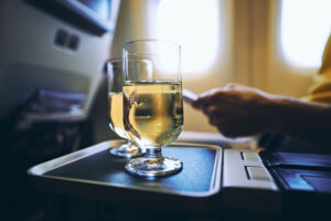 Two drinking glasses of sparkling wine against airplane window.