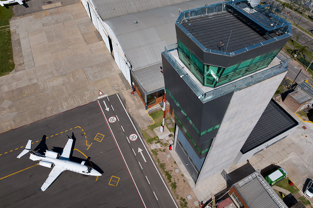 Aerial view of an airport with planes parked on the runway next to the control tower.