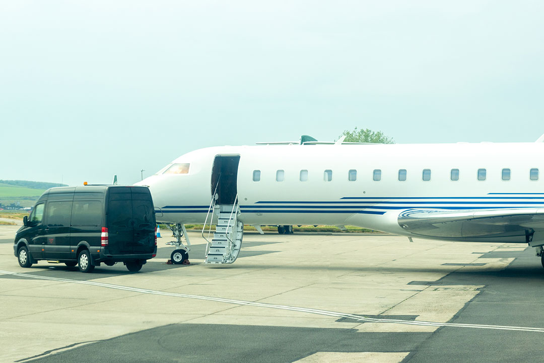 A private jet with an open door, greeted by a dedicated ground vehicle on the tarmac.
