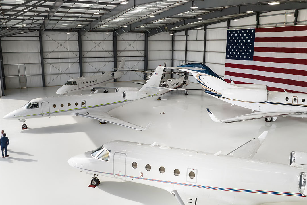 An aircraft hangar filled with luxury, private planes.