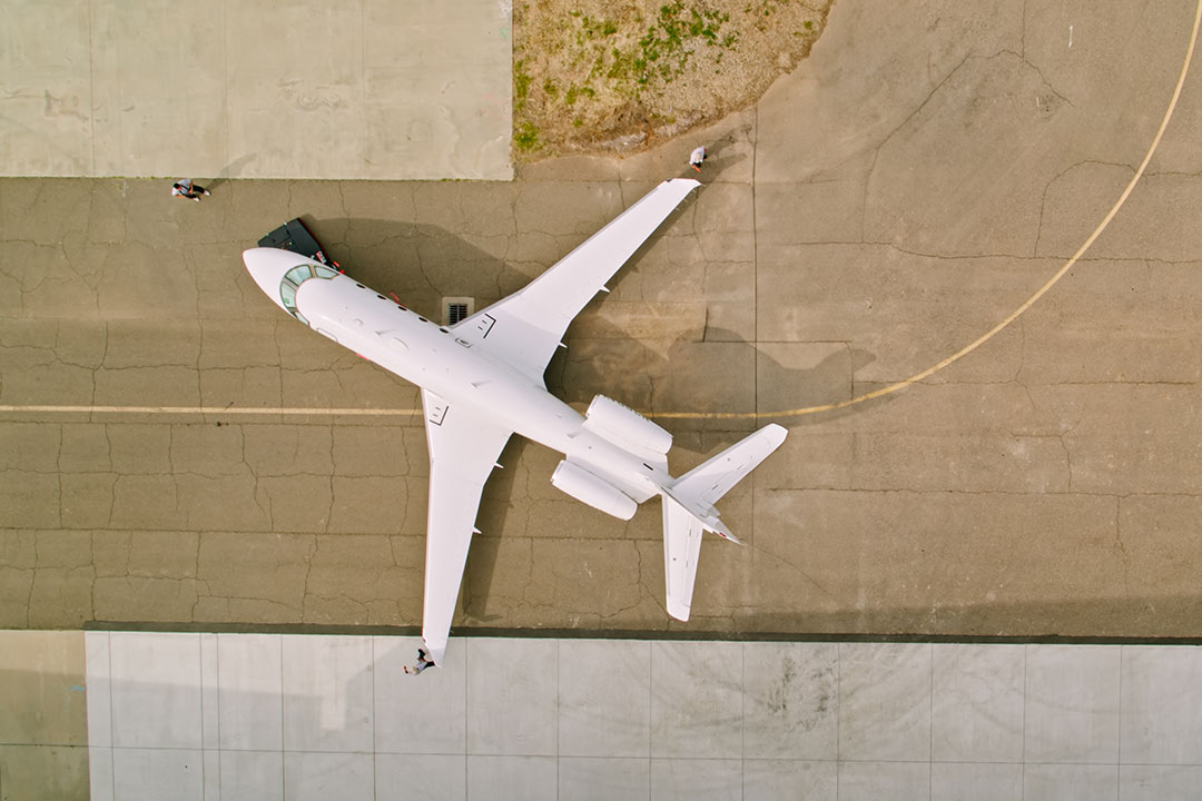 A private jet aircraft is positioned on the tarmac by the ground crew.