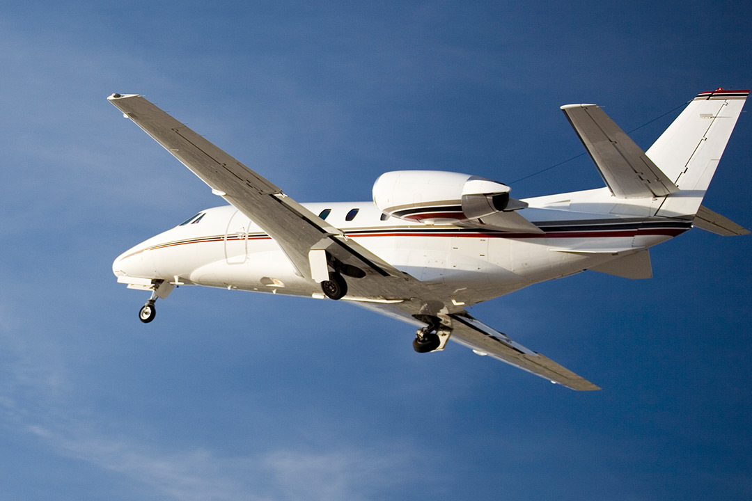 Light private jet in flight against clear blue sky