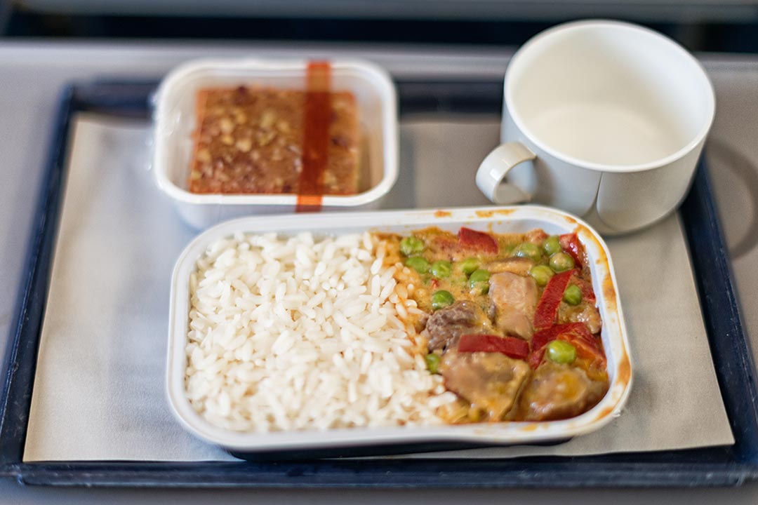 Standard airline fare built around strict cost controls and industrial durability, where lukewarm, mass-packaged food rarely lives up to its description.