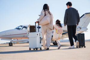 A family walks directly to their private jet flight with luggage in hand.